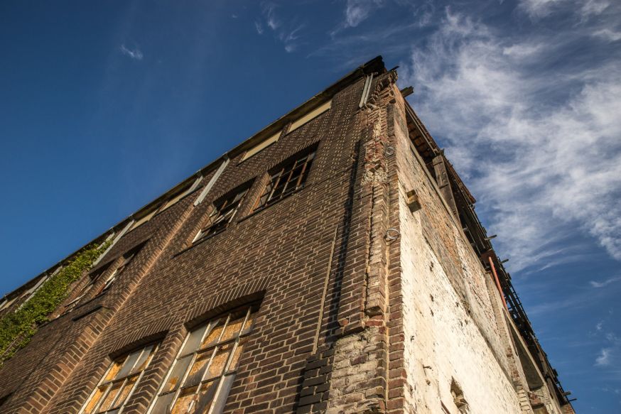 Afbeelding: Bakstenen gebouw van onderaf gefotografeerd, met sterke perspectiefwerking en lijnen die naar elkaar toe lijken te lopen