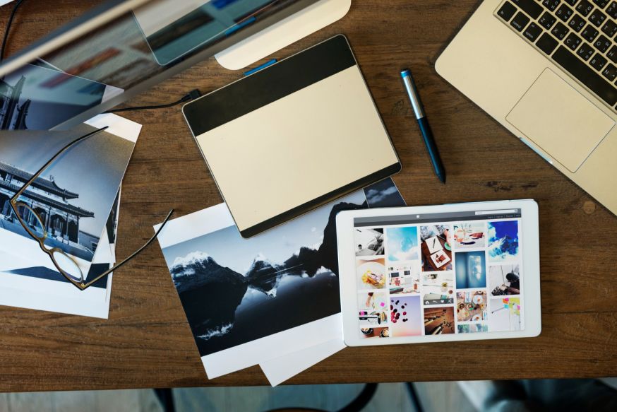 Afbeelding: Handen houden een tablet vast waarop een digitaal fotografie portfolio met een grid van diverse creatieve foto's wordt getoond