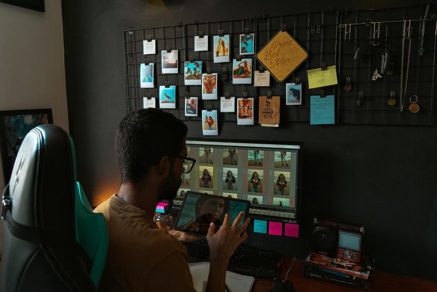 Afbeelding: Fotograaf bewerkt beelden in een thuiskantoor, waarbij AI bij fotografie wordt ingezet voor een snelle en consistente nabewerking op de computer
