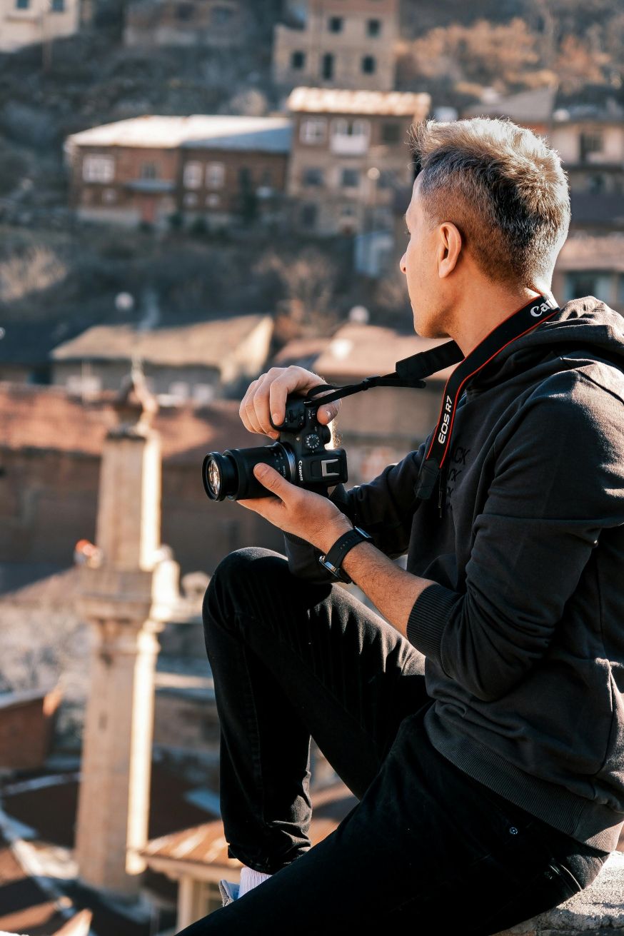 Afbeelding: Fotograaf kijkt met camera in de hand naar een verticale bouwvorm in de stad om eerst standpunt en compositie te beoordelen